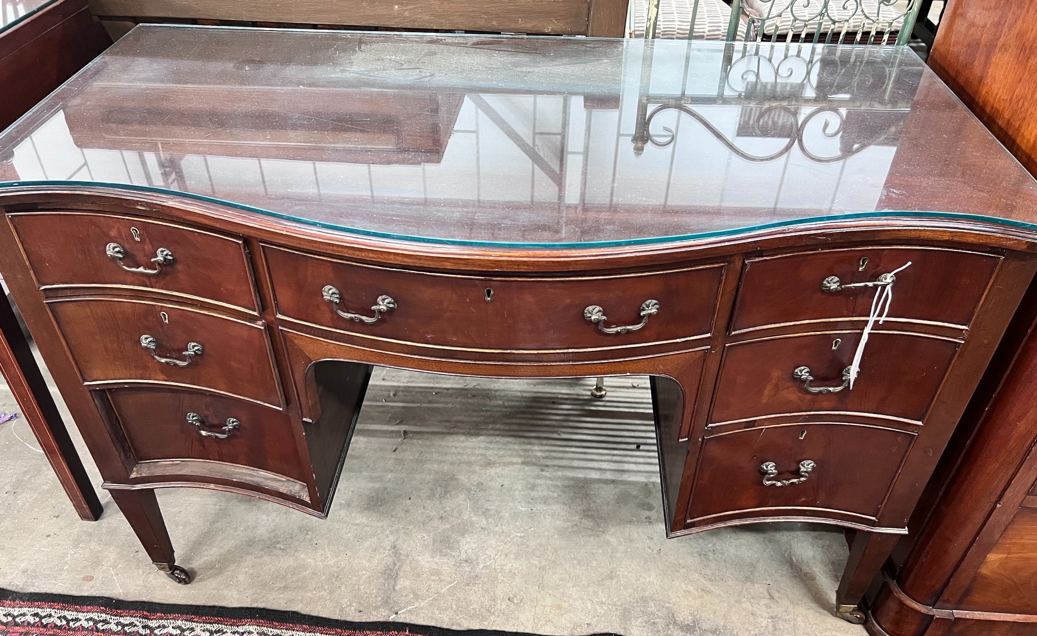 A 1920's serpentine mahogany kneehole dressing table, width 120cm, depth 61cm, height 76cm *Please note the sale commences at 9am.